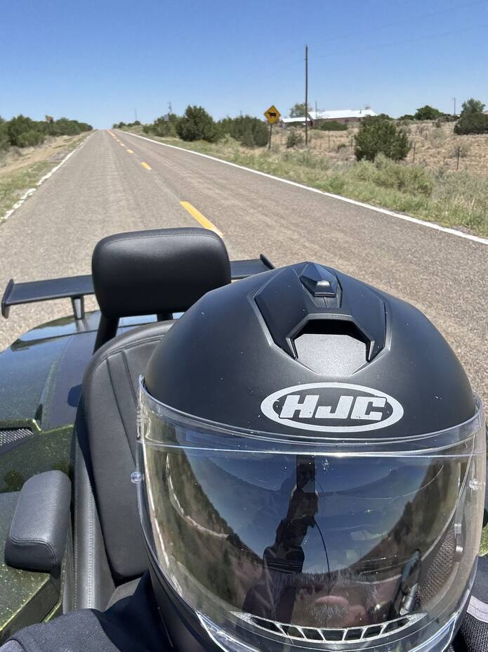 Helmet resting on the trike beside a desert road