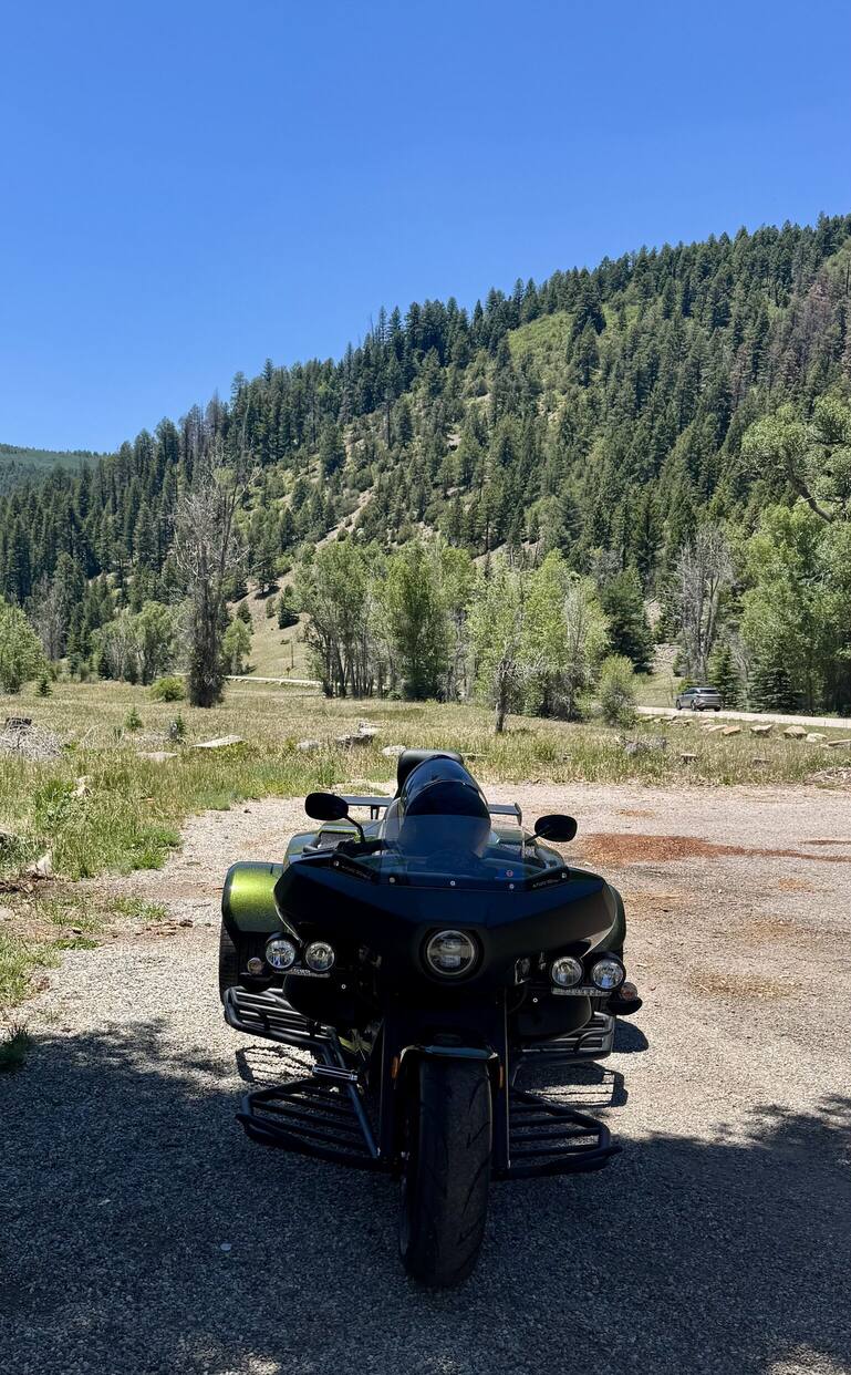 Rewaco trike parked below a pine-covered mountain
